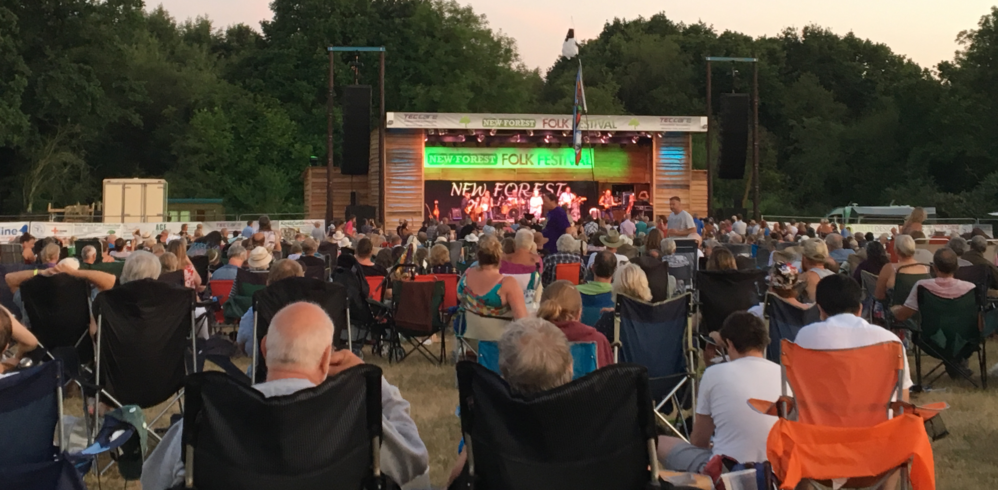 A large crowd in a field watching one of the bands perform.