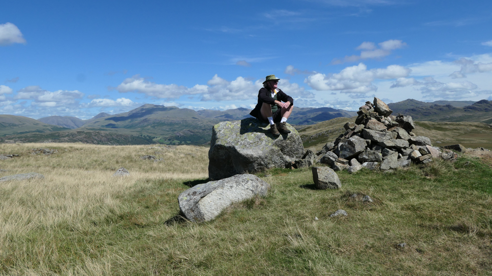 Kevin sitting on a large rock at the top of one of the hills overlooking Devoke Water.