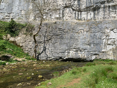 Malhan Beck appearing from a cave at the bottom of the cliff.