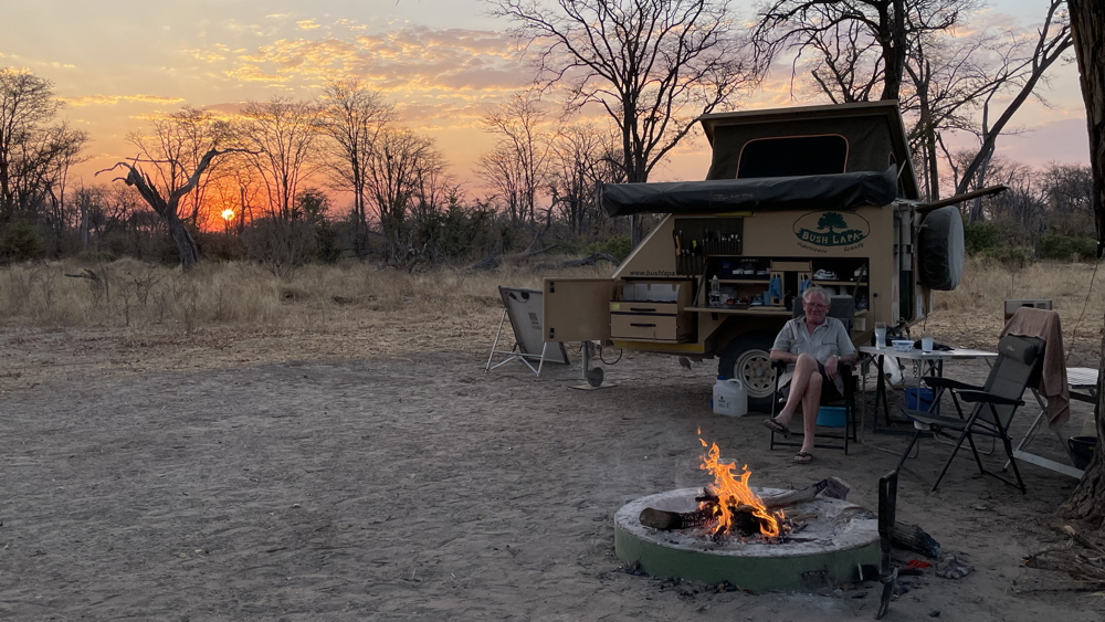 Kevin sitting by the fire with the sun setting in the distance.